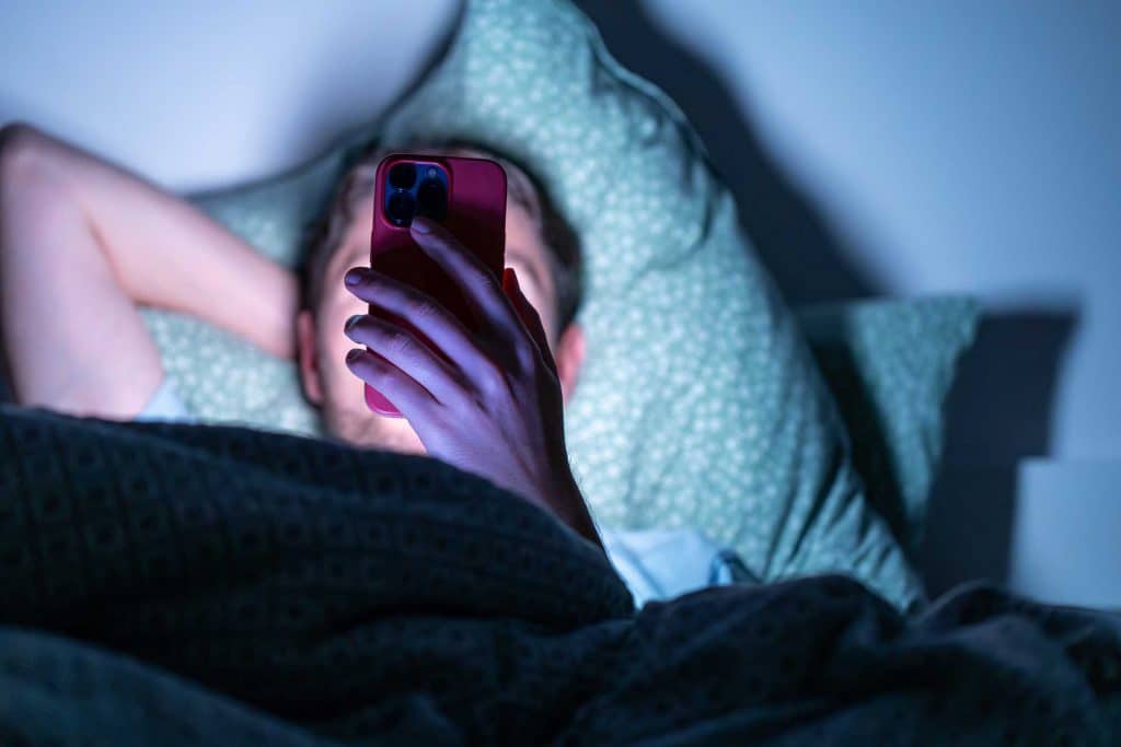 A man holding a phone, highlighting concerns about screentime and its potential impact on droopy eyelids - Cienna Aesthetics Medical Clinic